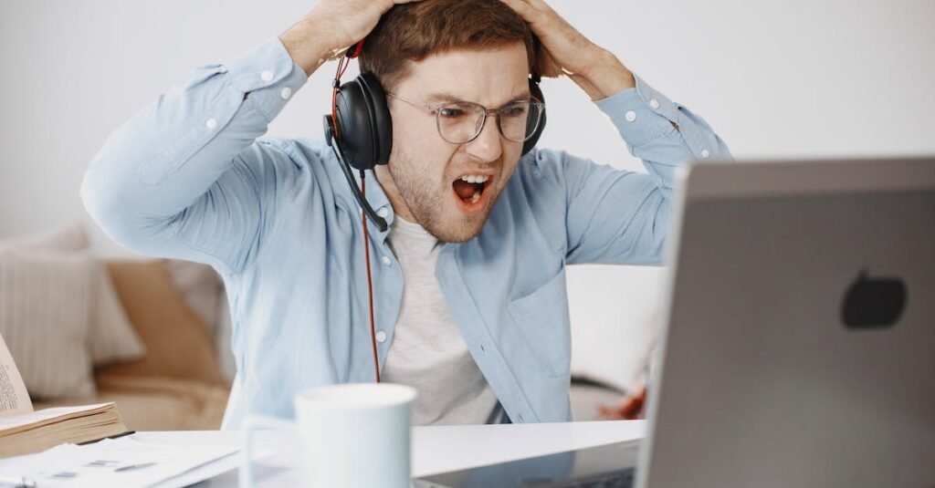 Man experiencing frustration at home office while working on laptop.