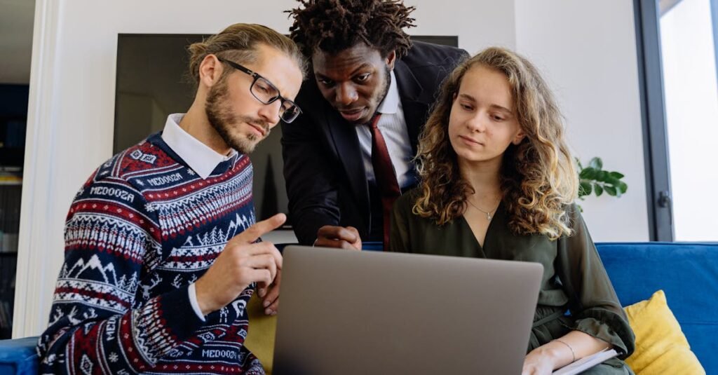 A diverse team of professionals collaborating on a laptop in a modern office setting.